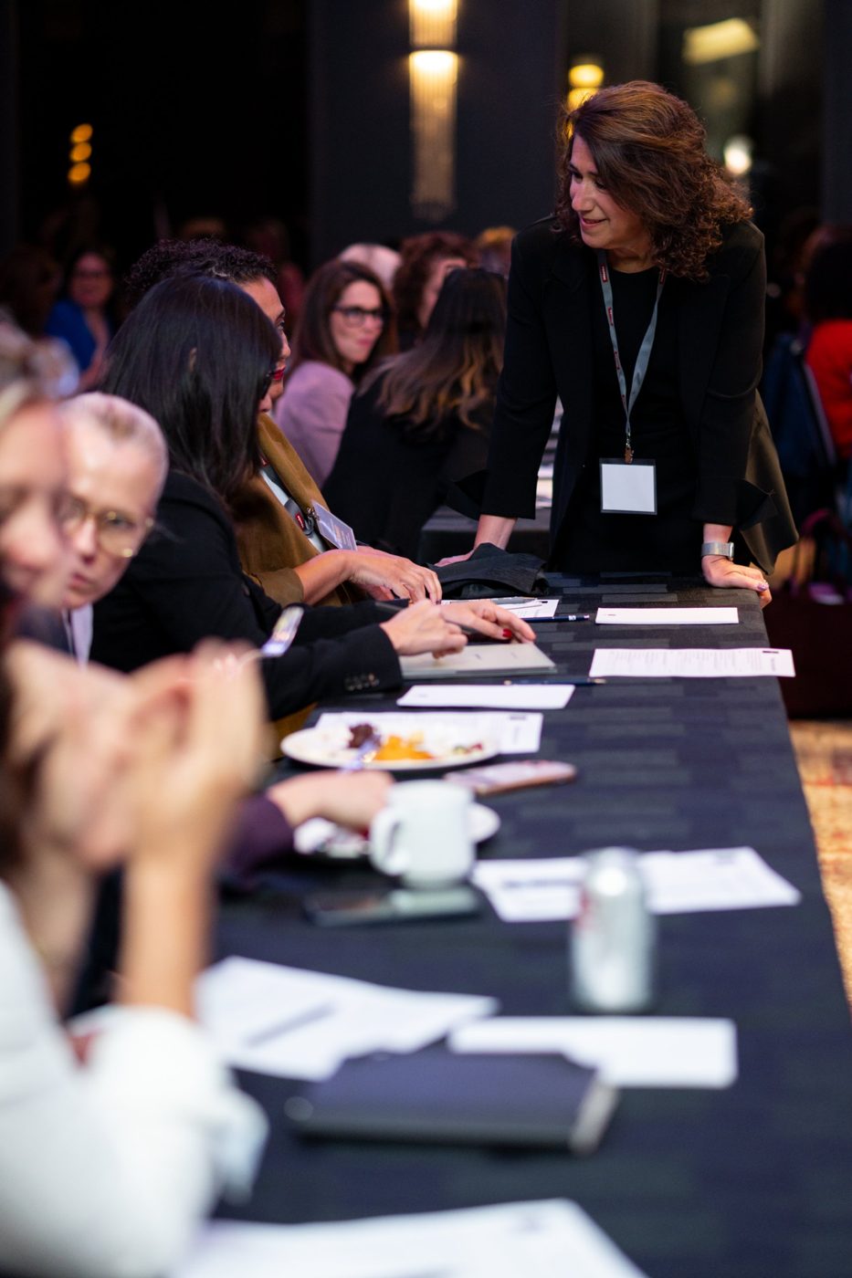 Sara Curwen leaning in to talk with participants at a workshop table