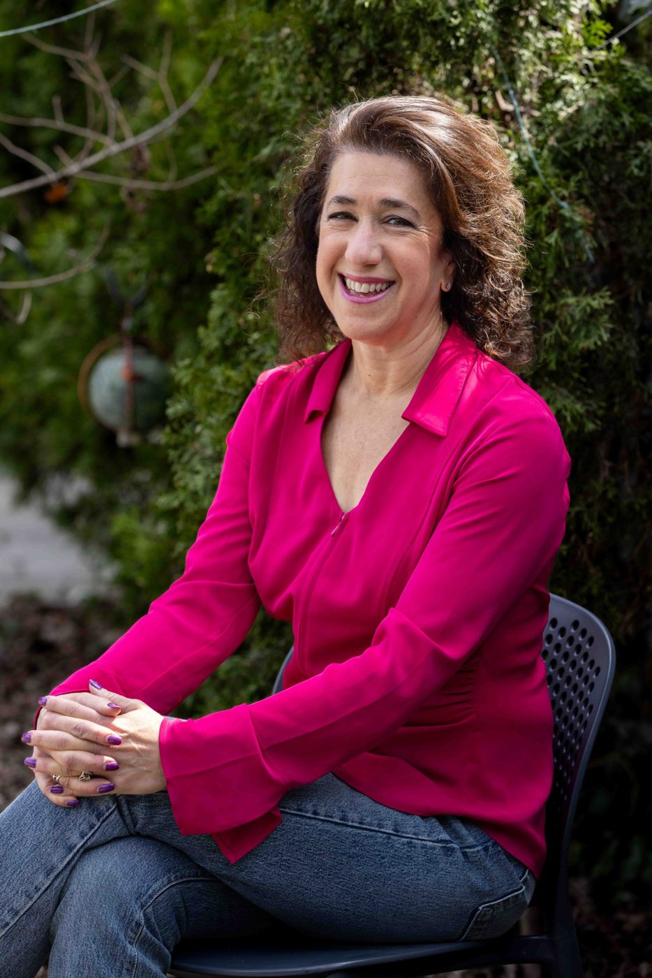 Sara Curwen smiling, seated outdoors in a garden